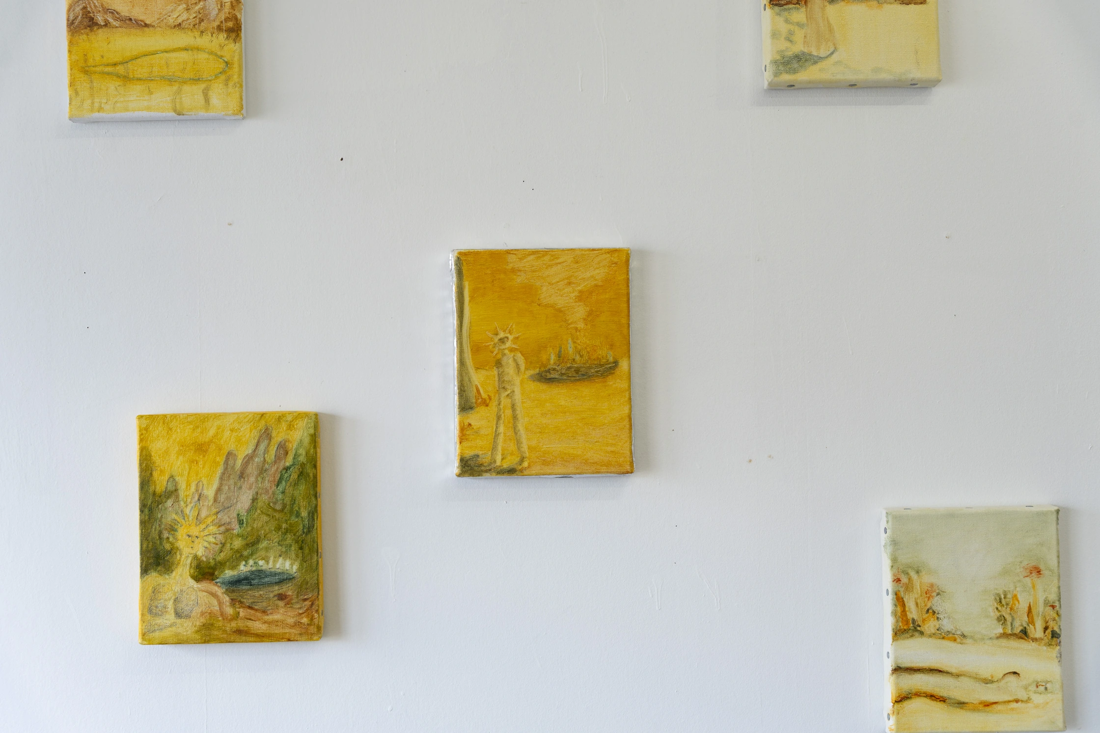 白い壁に展示された黄色系の絵